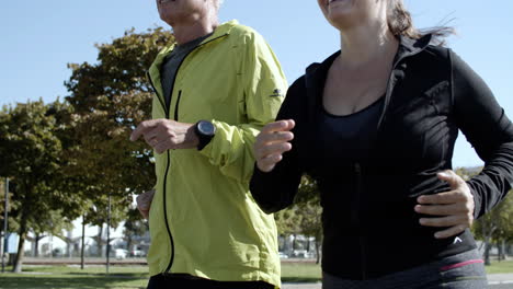 couple of happy middle aged runners jogging down street