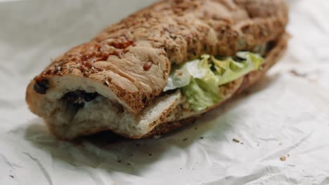 sub sandwich moving close up showing toasted bread with cheese with lettuce cucumber steak