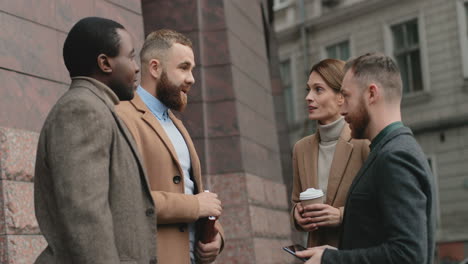 Hombres-De-Negocios-Multiétnicos-Y-Mujeres-De-Negocios-Caucásicas-Tomando-Un-Café-Juntos-En-La-Calle-Y-Discutiendo-Sus-Planes-Y-Su-Nuevo-Proyecto-De-Negocios