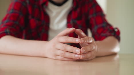 woman taps clasped fingertips at table closeup young employee worries at meeting with supervisor in