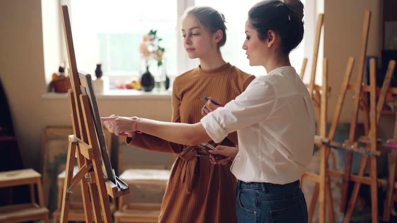 두 명의 여성이 미술 스튜디오에서 그림을 그리고 있습니다.