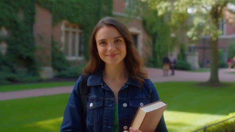 happy young woman student holding a book on university campus