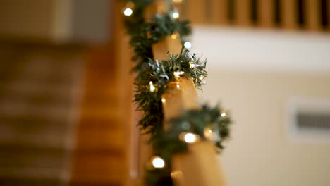 garland with christmas lights on wooden railings of stairs in the house