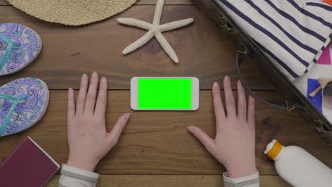 overhead aerial of woman touching smart phone by beach supplies