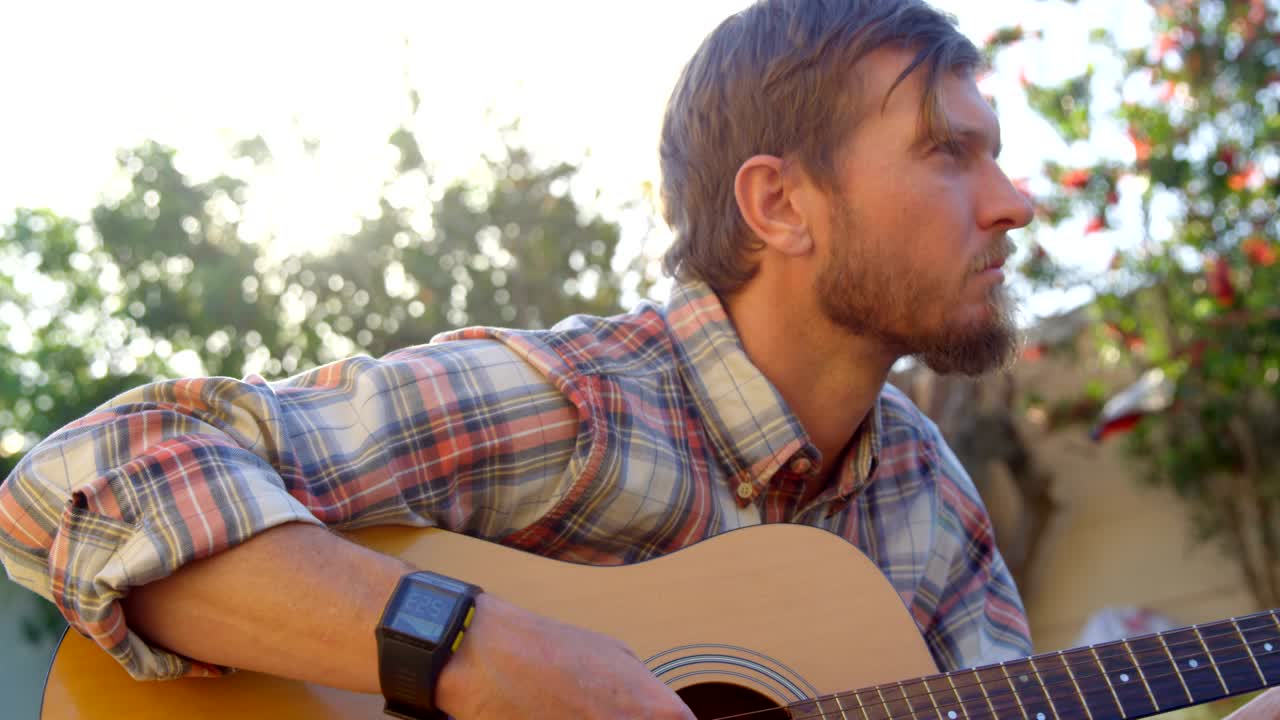 Homem tocando violão no jardim 4k