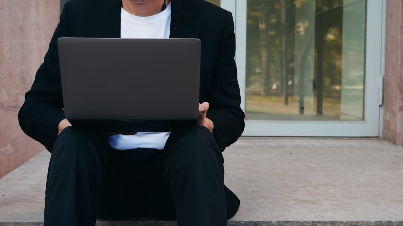 Asian businessman using laptop computer in the park, man working outdoor near modern office. Park street airport terminal