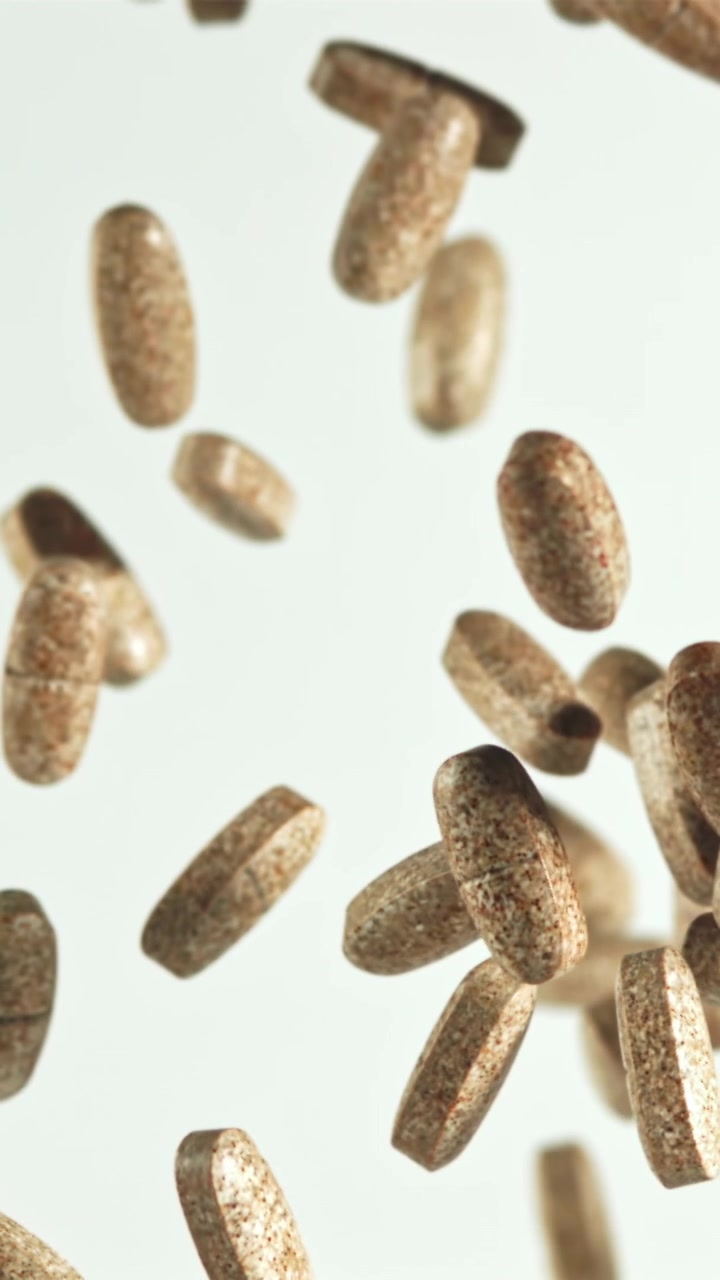 Brown Pills Falling in Slow Motion Against White Background