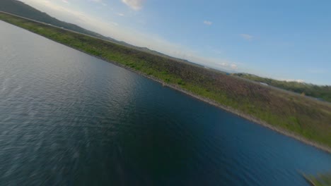 Daring-FPV-drone-flight-right-under-cement-pump-station-on-dam,-sunset