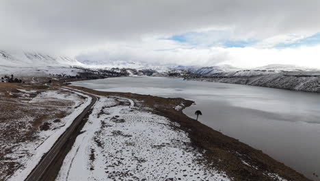 aerial drone over patagonian winter lake and remote volcanic route in caviahue, argentina