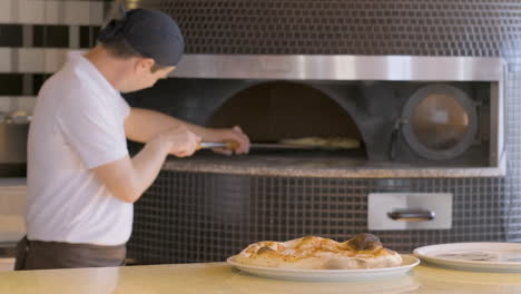 chef moviendo pizza con cáscara en el horno despedido