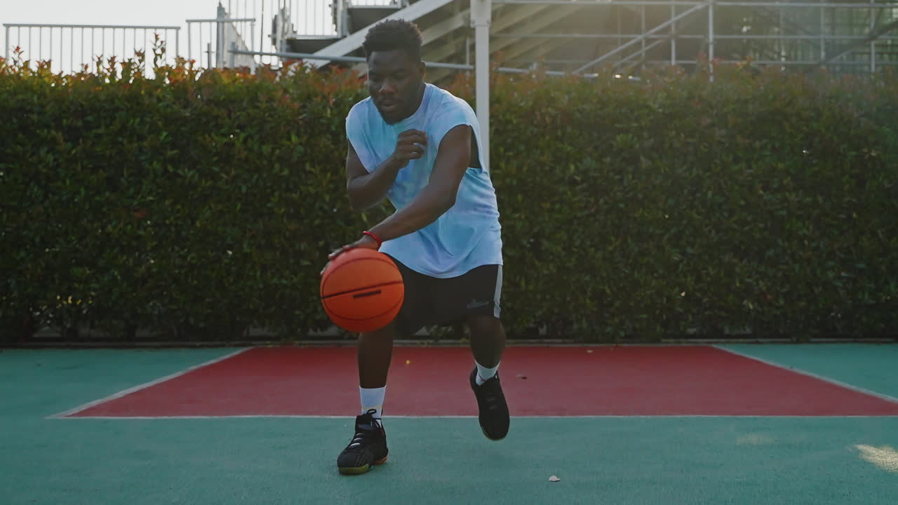 Man Dribbling Basketball on Outdoor Court