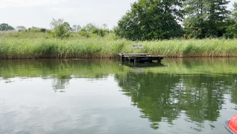 Old-wooden-bridge-over-the-lake-with-a-small-bench-on-it