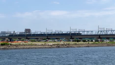 A-train-travels-over-a-bridge-on-a-sunny-day-with-a-city-skyline-in-the-background