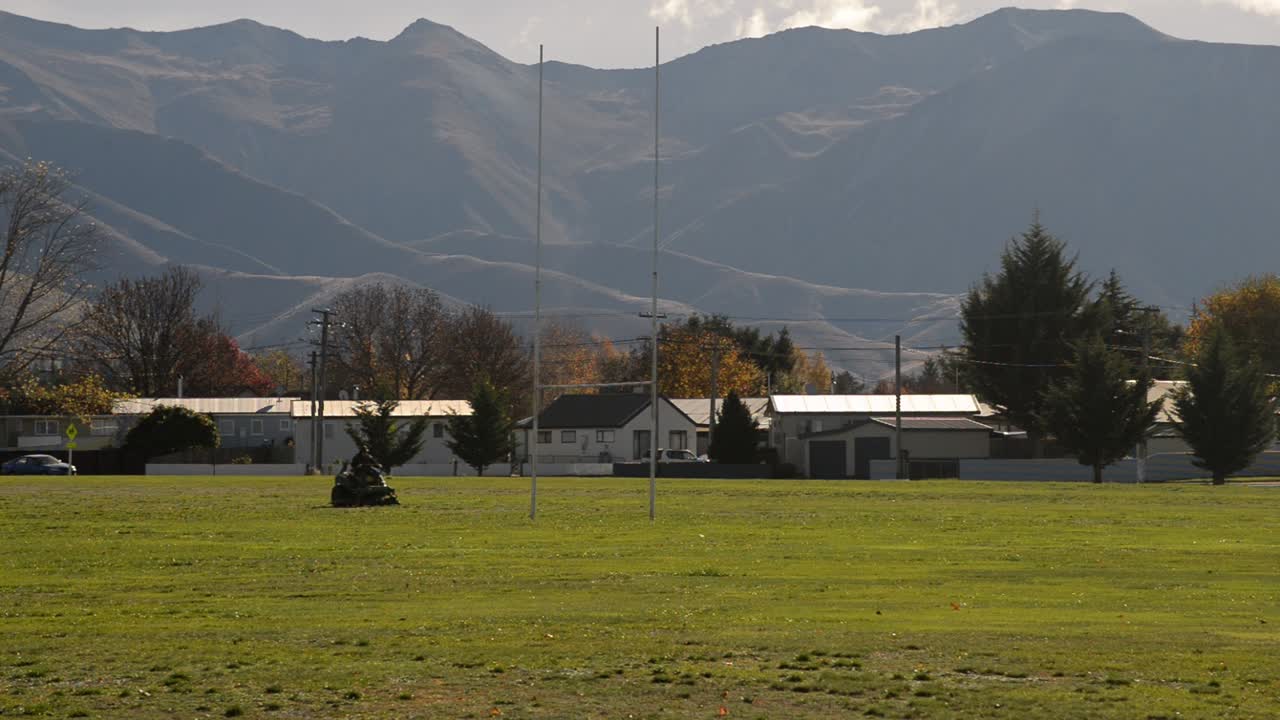 hombre en un cortador de césped cortando un campo de fútbol