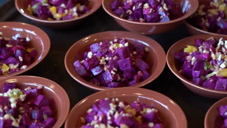 bowls of vibrant purple beet salad topped with chopped garlic or onions, close up shot