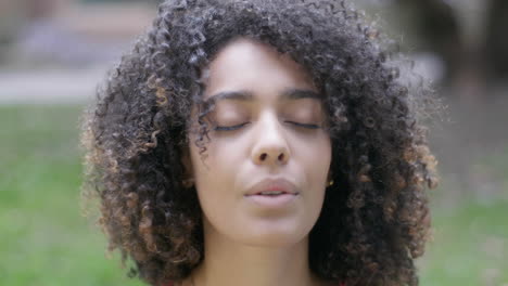 close up shot of calm and comfortable expression of a curly haired girl doing yoga and enjoying the clean air in the morning