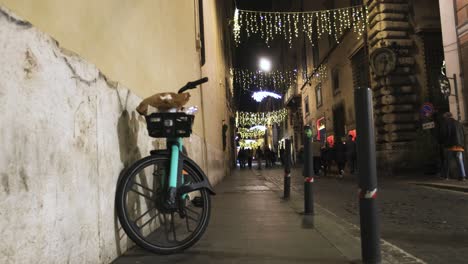 street in rome, italy at night with bicycle and pedestrians with an establishing shot