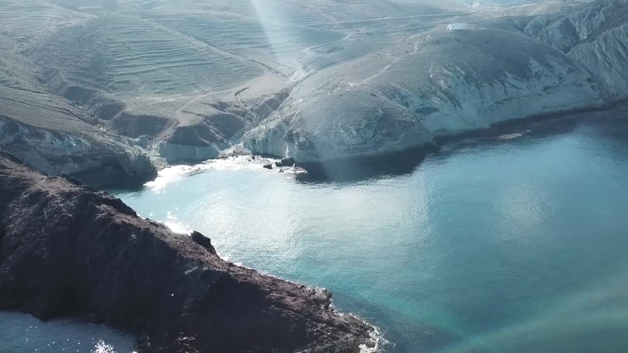 Vertical drone shot capturing the rough texture and unique shape of a solitary rocky island in the Mediterranean Sea