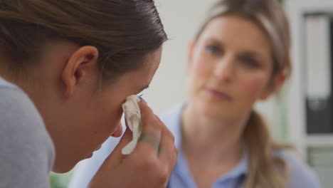 primer plano de un médico hablando con una paciente adolescente que llora y sufre de problemas de salud mental.