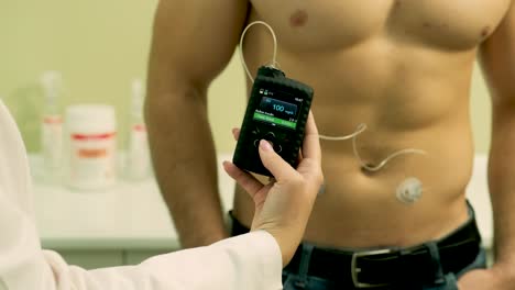médico con una bomba de insulina conectada en el abdomen del paciente y sosteniendo la bomba de insulina en sus manos. concepto de diabetes.