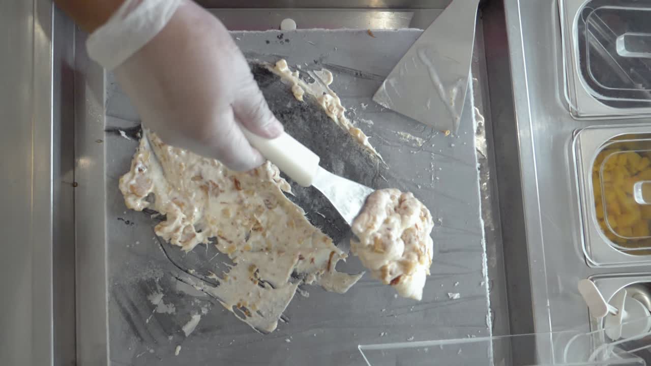 쿠키가 뒤집힌 바닐라 아이스크림은 주걱으로 차가운 그릴에 퍼지고 천천히 움직입니다.