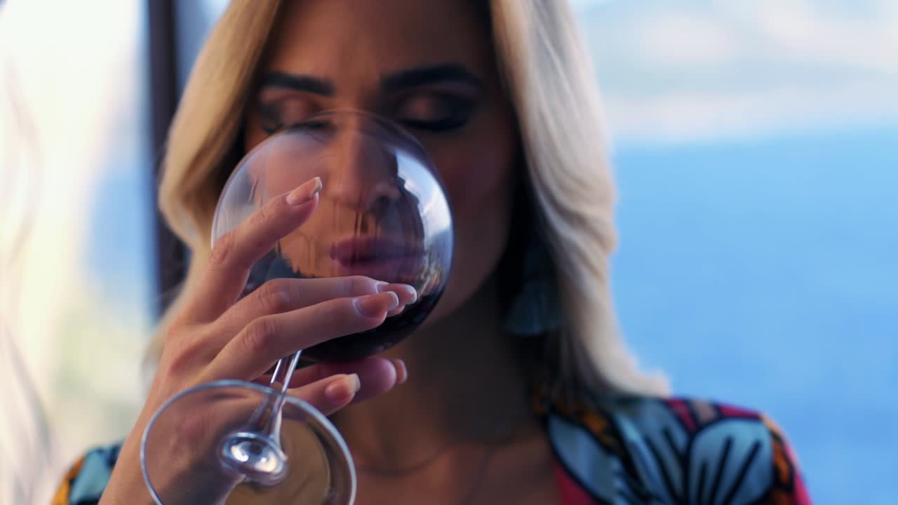 model woman drinking red wine while looking at camera