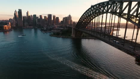 aerial pan and tilt towards sydney harbour bridge at sunset, city in background