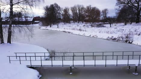 beautiful frozen ice lake aerial view reverse over snowy park bridge landscape