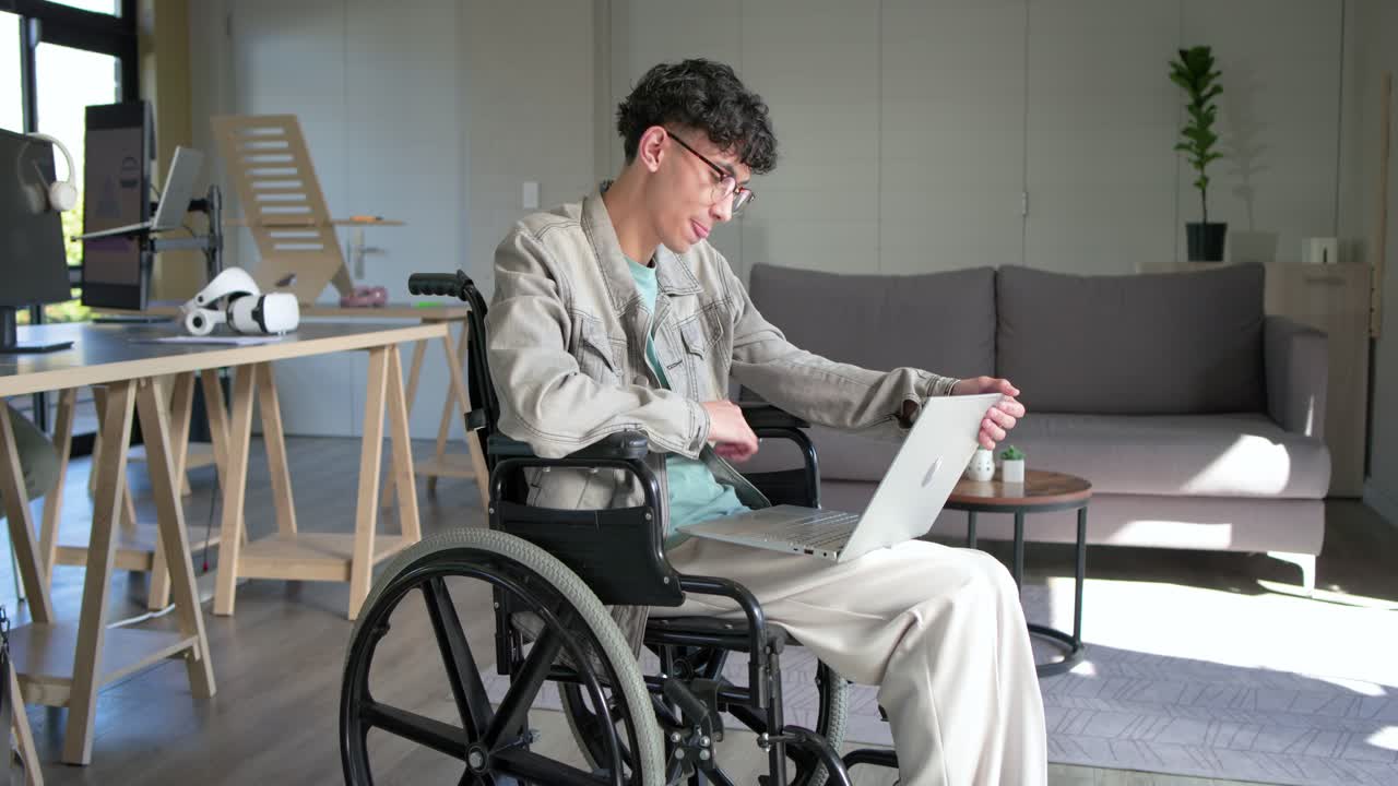 Pondering report, mid adult man in wheelchair sitting upright and typing on laptop at office lounge