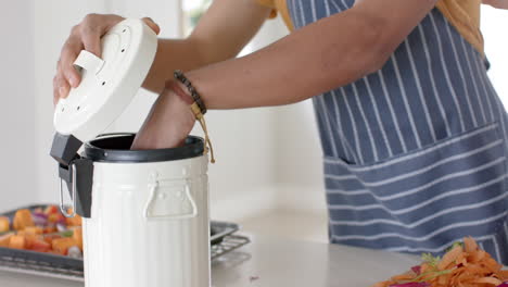 Biracial-man-with-fresh-vegetables-on-table-throwing-waste-out-in-kitchen,-slow-motion