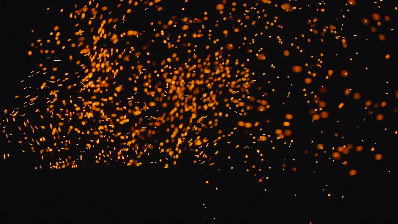 Sparks from bonfire over dark night environment, shallow focus. Burning ash rise from fire in the night sky. Beautiful abstract background on the theme of fire, light and life. Sparks fly in up