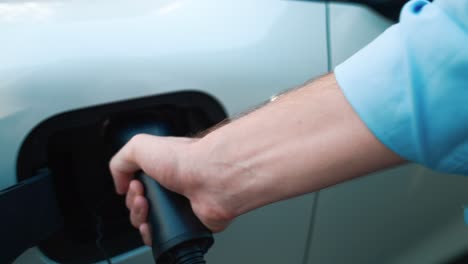 Progressive-businessman-plugs-charger-plug-from-charging-station-to-his-EV.