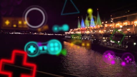 Animated-colorful-gaming-icons-over-illuminated-waterfront-at-night