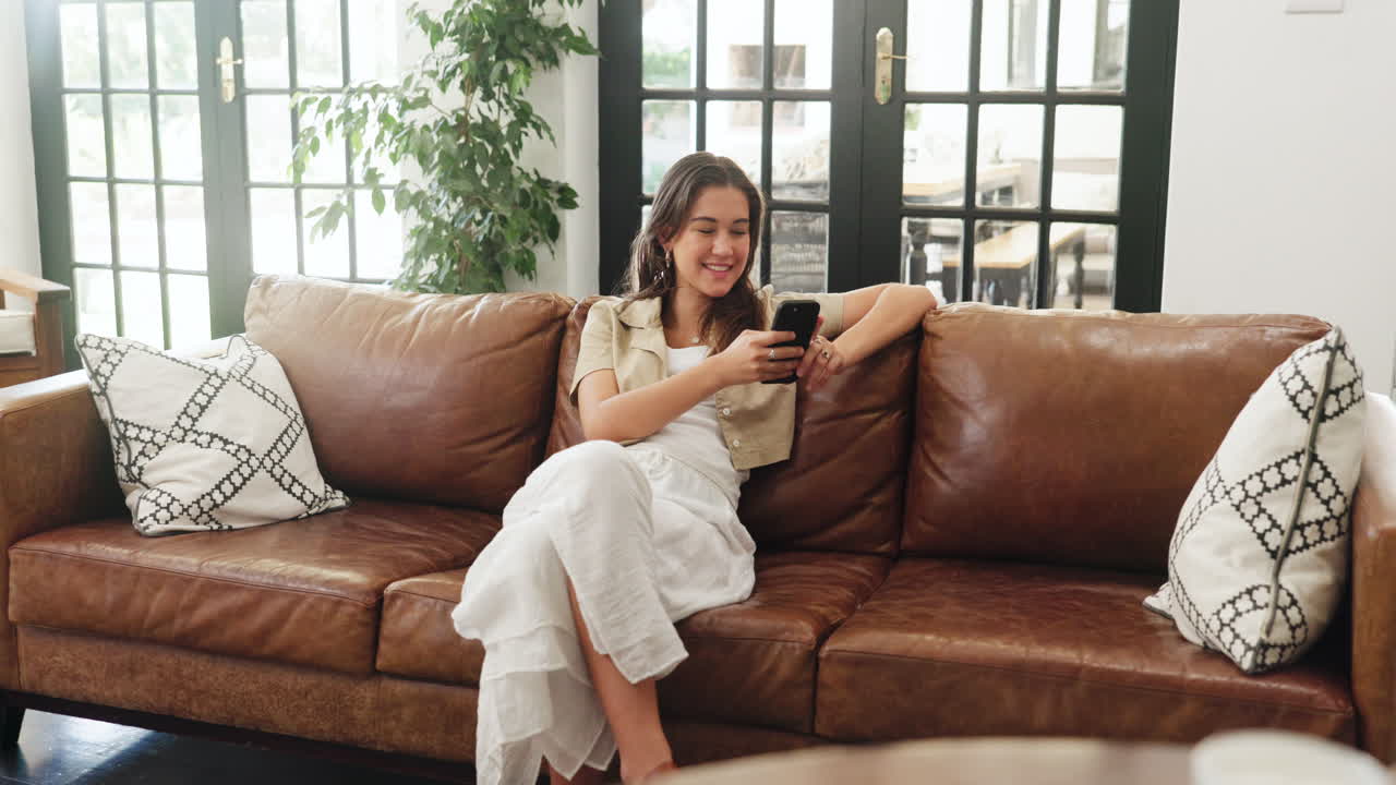 Giovane donna che si rilassa sul divano e usa lo smartphone a casa