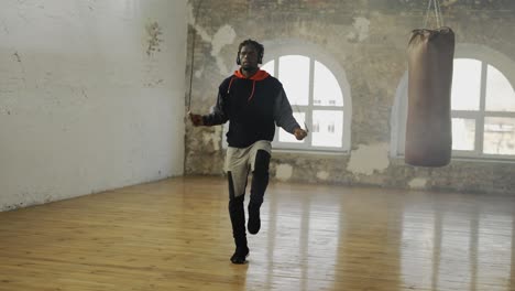 african american man skipping the rope in and empty hall, listen music