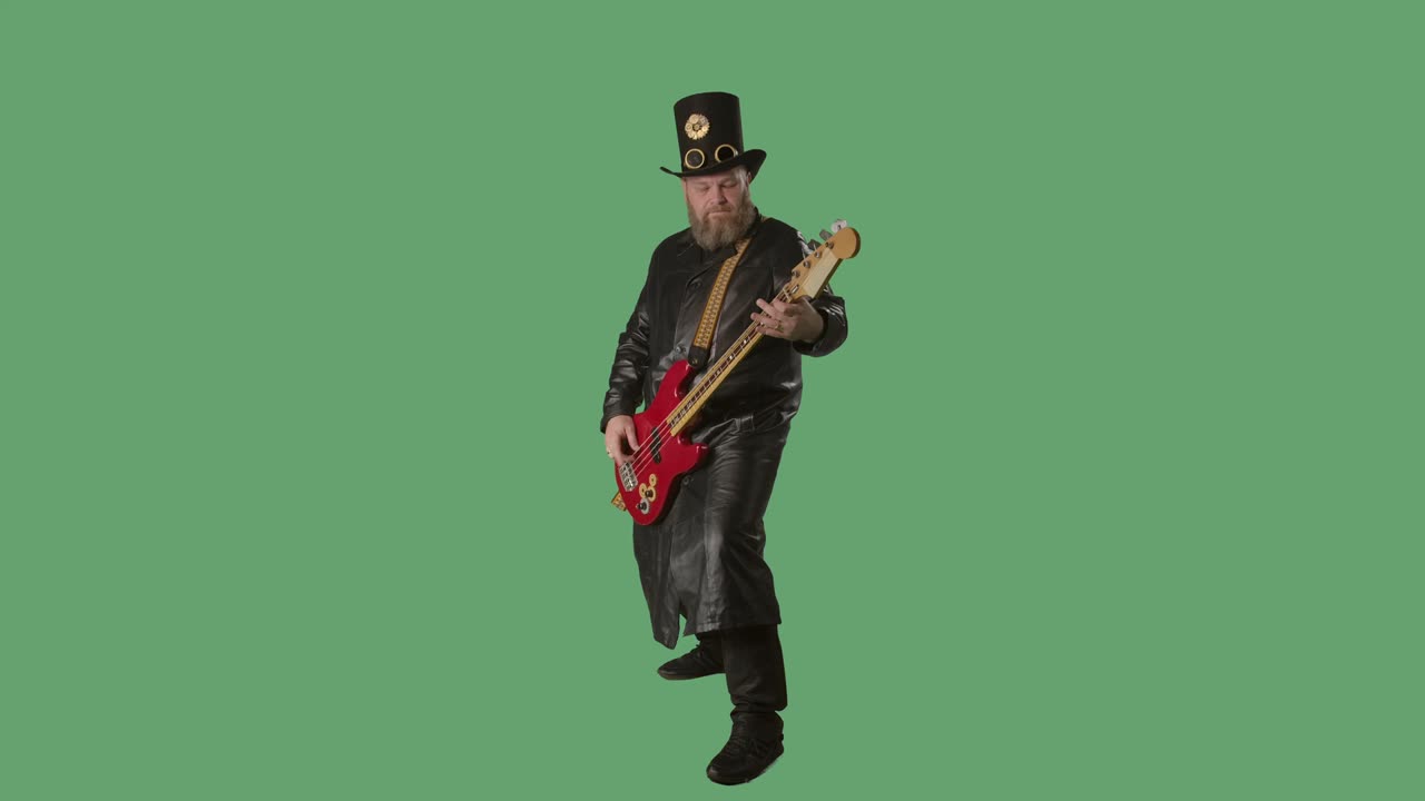 Un uomo barbuto con un lungo cappotto di pelle e un cappello in stile irlandese suona la chitarra rossa. Musicista rock suona il basso in studio su schermo verde chroma key. Slow motion.