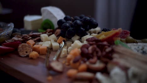 tablero de charcutería con nueces, frutas, quesos y galletas