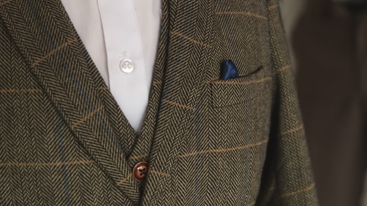 Close up of green checkered three piece tweed wedding suit for men presented on mannequin at wedding fair market event.