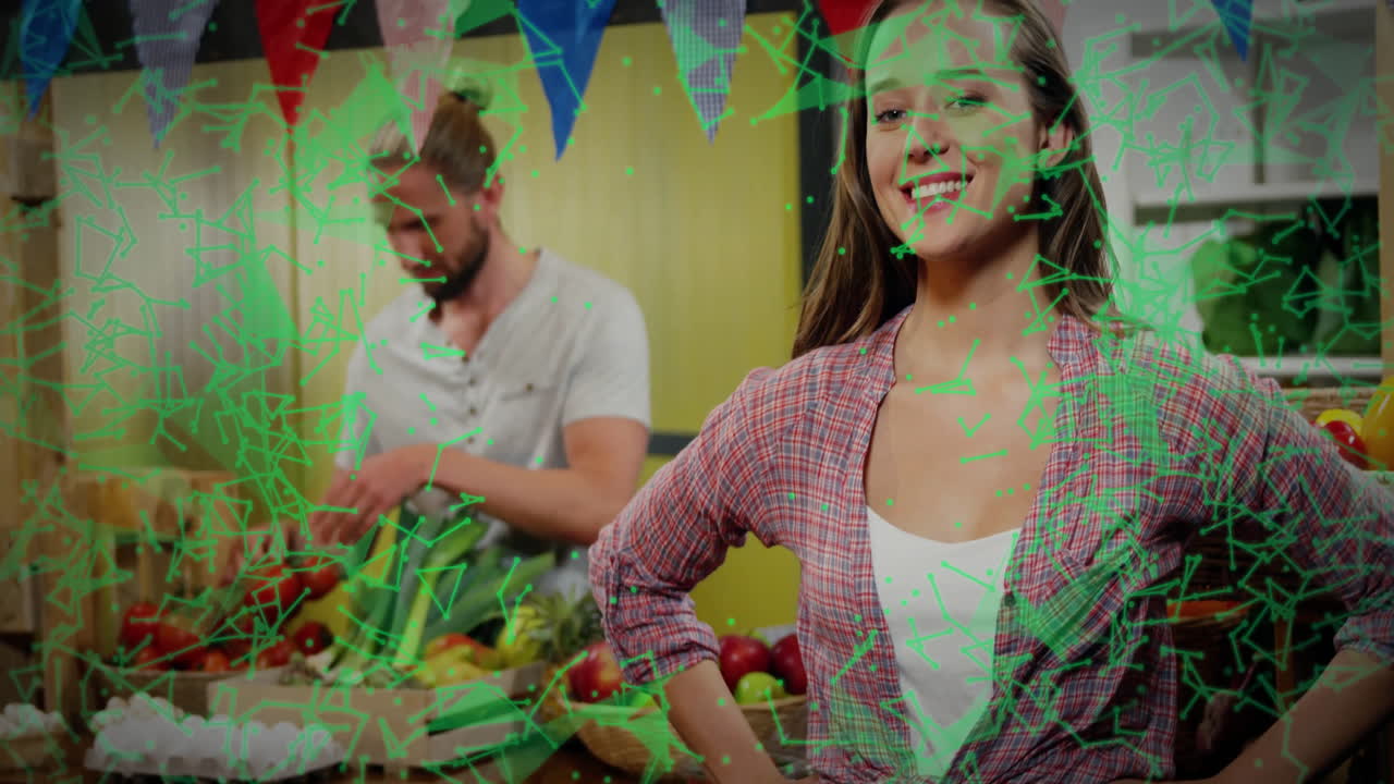 Smiling woman in kitchen with green network animation over cooking man