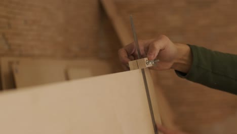 hardworking professional carpenter hands holding a ruler while measuring a wooden plank, plywood panel in a carpentry workshop