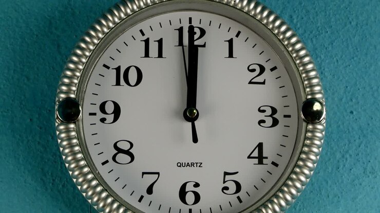 Quartz wall clock with second hand runs clockwise. The clock shows twelve o'clock.