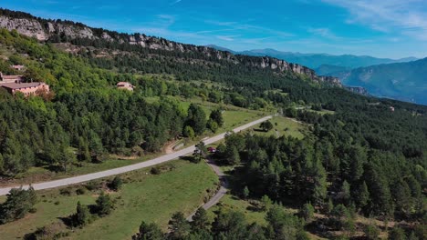 Red-Car-stopped-at-intersection-of-two-roads-in-middle-of-the-mountains,-Catalonia