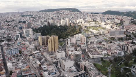 drone shot of the city of quito, ecuador. overlooking park parque el ejido and casa de la cultura during quarantine. buildings, houses and hills on the back. empty streets with no cars.
