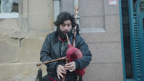 un artista callejero que no es de escocia muestra sus habilidades para tocar la gaita