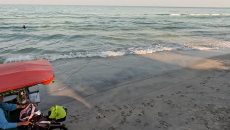 vendor riding a motorbike on the beach at sunset