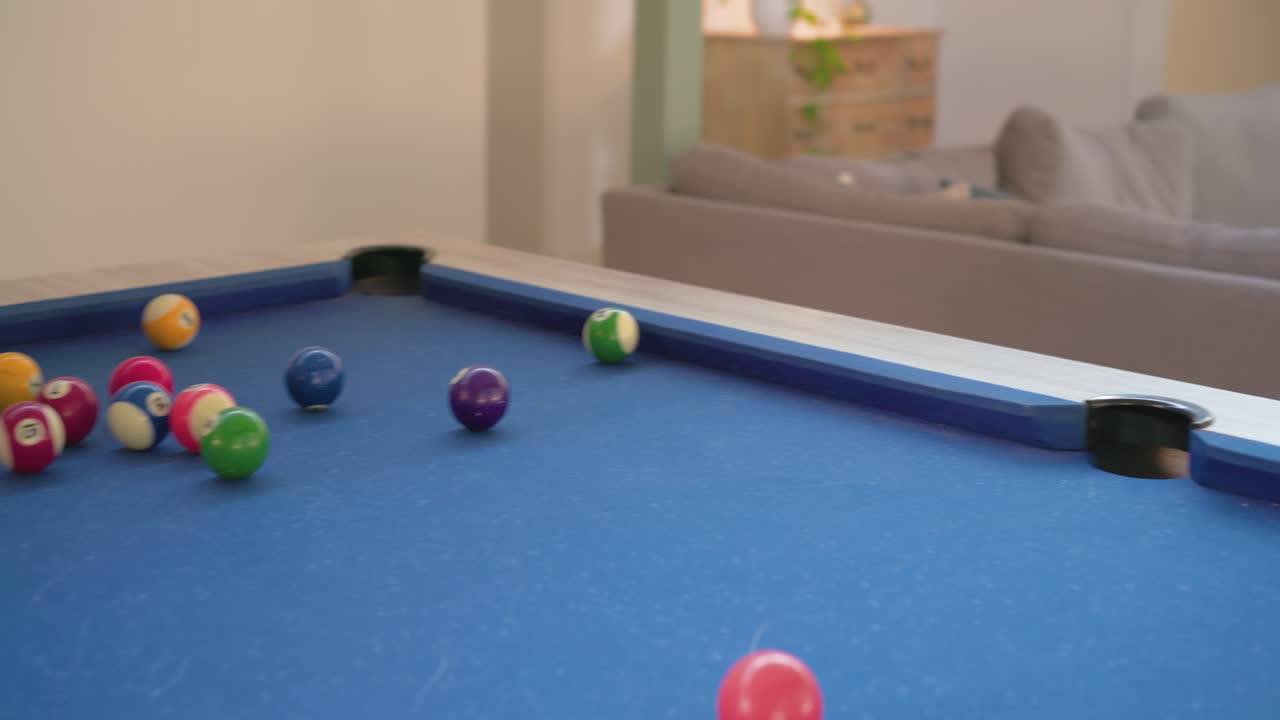 Man bridging cue on pool table at home, chalking, breaking balls to start game, copy space