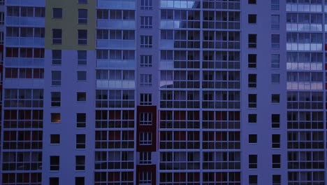 drone view of colorful facade contemporary apartment building, windows and balconies. aerial footage highrise estate at night time.