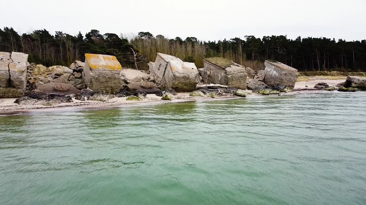 вид с воздуха на заброшенные приморские фортификационные сооружения северных фортов кароста на берегу балтийского моря в лиепае в пасмурный весенний день, широкая съемка с беспилотника, движущегося вперед над спокойным морем