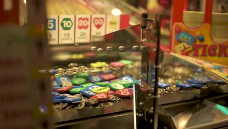 arcade coin pusher, dropping and pushing coins with tickets coming out, slow motion