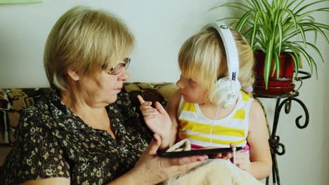 la abuela y la nieta se divierten juntos, usan una tableta